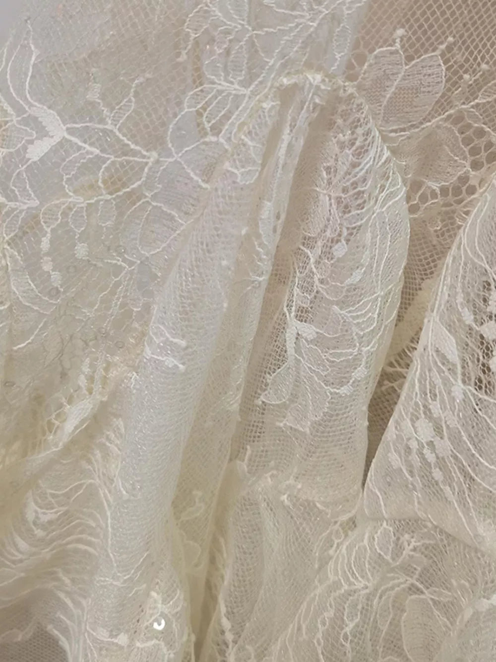 White floral lace dress fabric with ruffle detail and subtle sequins.