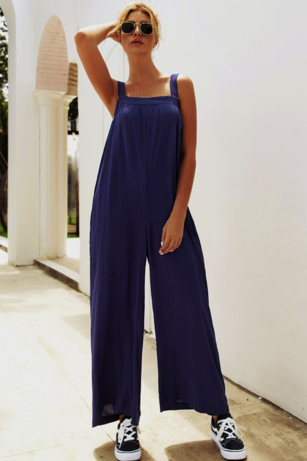 Dark blue square-neck palazzo jumpsuit with wide legs and pockets.
