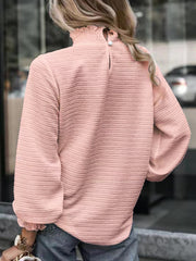 Dusty pink textured blouse with smocked mock neck and puff sleeves.