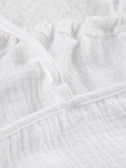 White cotton cami pajama top detail with adjustable strap and textured fabric.