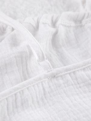 White cotton cami pajama top detail with adjustable strap and textured fabric.