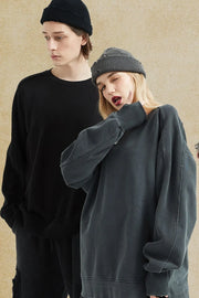 Oversized sweatshirt in dark gray with raw-edge seams and crew neck, styled casually.
