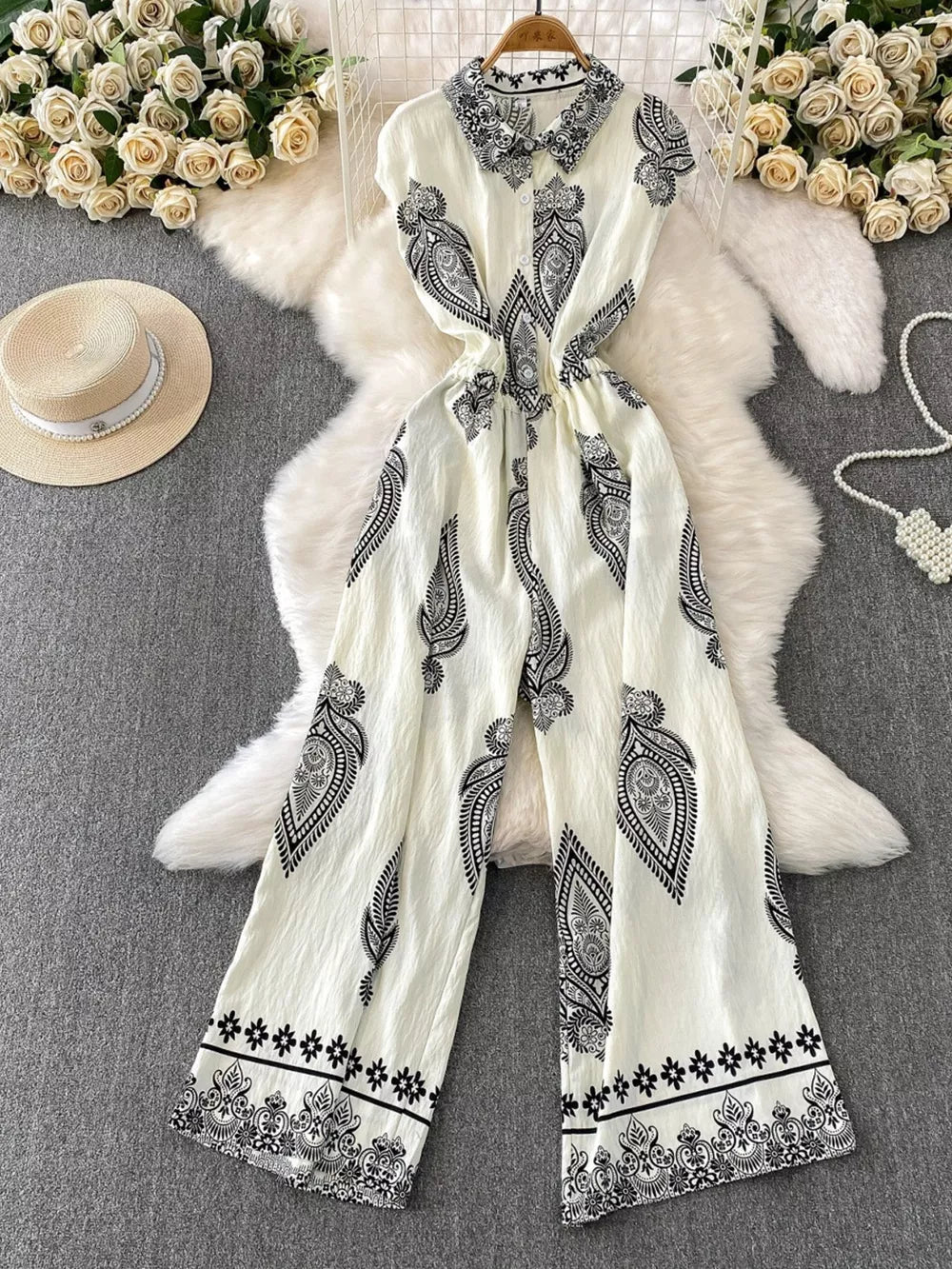 White wide leg romper with black paisley print, collared, button-down front, and cinched waist.
