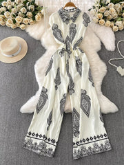 White wide leg romper with black paisley print, collared, button-down front, and cinched waist.