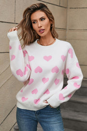 White acrylic sweater with pink heart intarsia pattern, crewneck, and long sleeves.