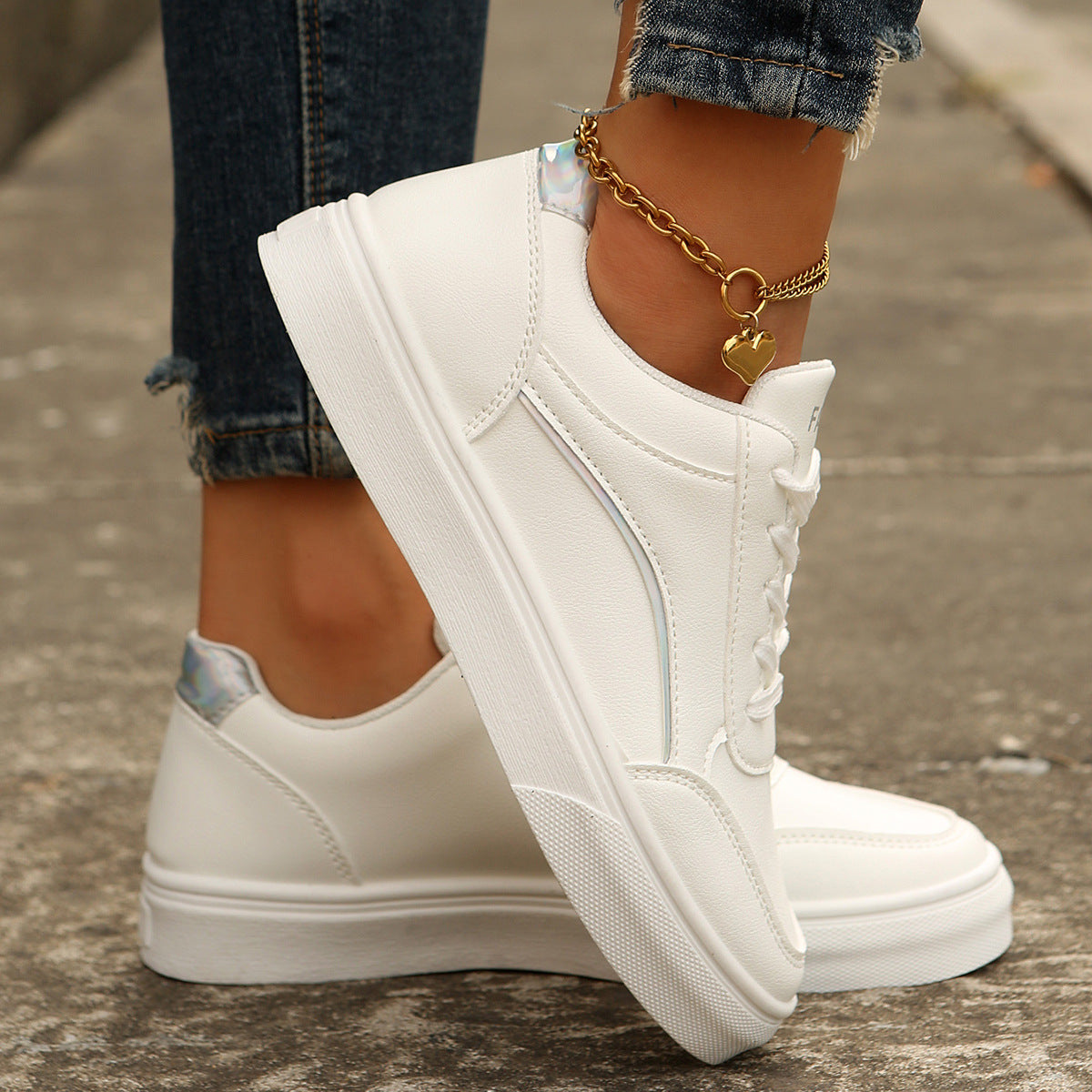 White lace-up casual sneakers with metallic heel accents and a heart charm anklet.
