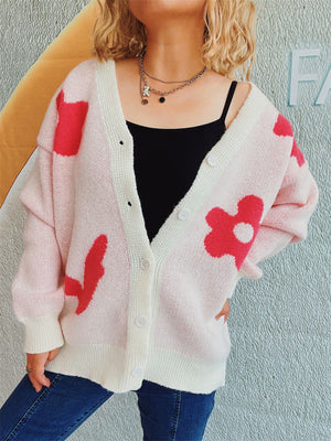 Blush pink acrylic cardigan with playful red floral appliqué and white trim.