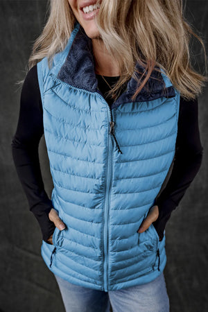 Quilted puffer vest in pastel blue with a dark blue fleece collar and zip front.
