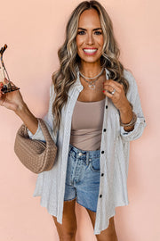 Relaxed white button-down shirt with blue pinstripes, open collar, and black buttons.
