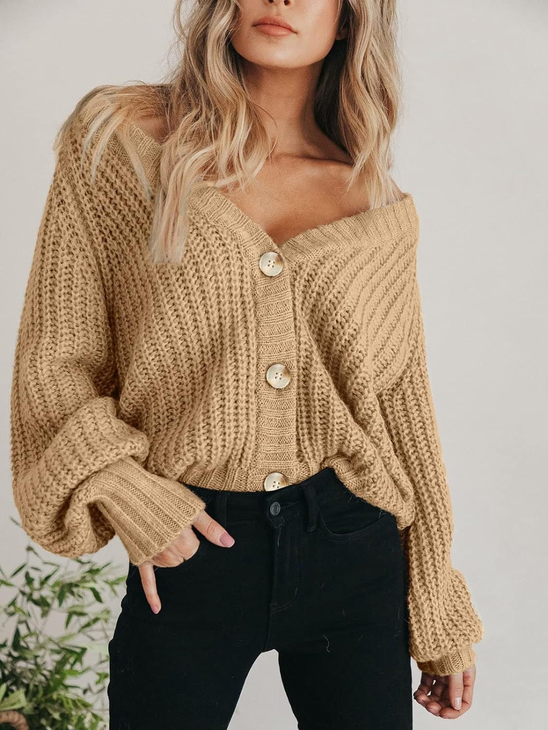 Camel knit cardigan with voluminous sleeves and button front, styled off-shoulder.