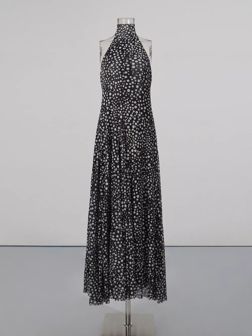Black and white polka dot halter maxi dress with a flowing skirt.
