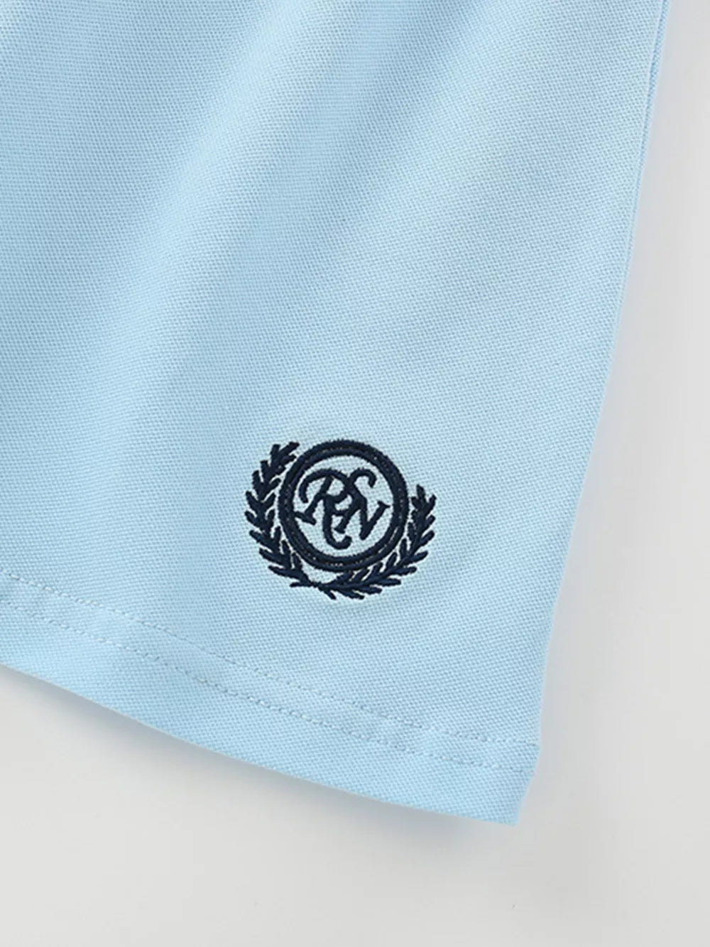Light blue cotton polo shirt detail with embroidered crest logo