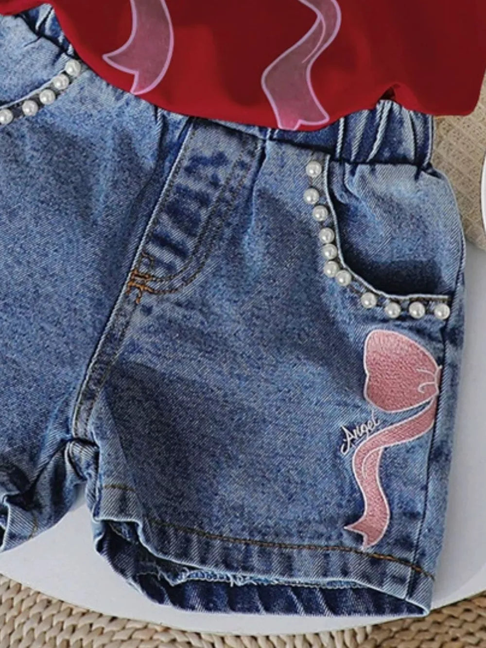 Denim shorts with pearl trim and pink bowknot embroidery, paired with a scarlet tee.
