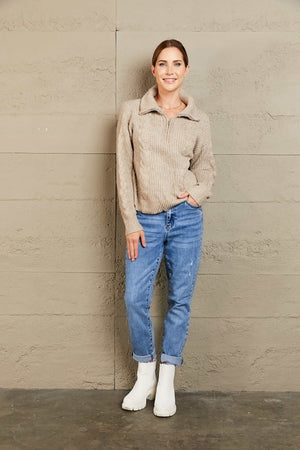 Oatmeal cable knit zip-up sweater with a stand-up collar.