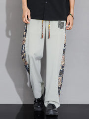 Men's light gray sweatpants with printed side stripes and drawstring.