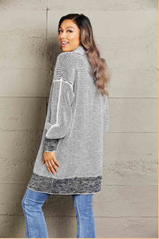 Textured open cardigan in black with puff sleeves and a patterned knit.