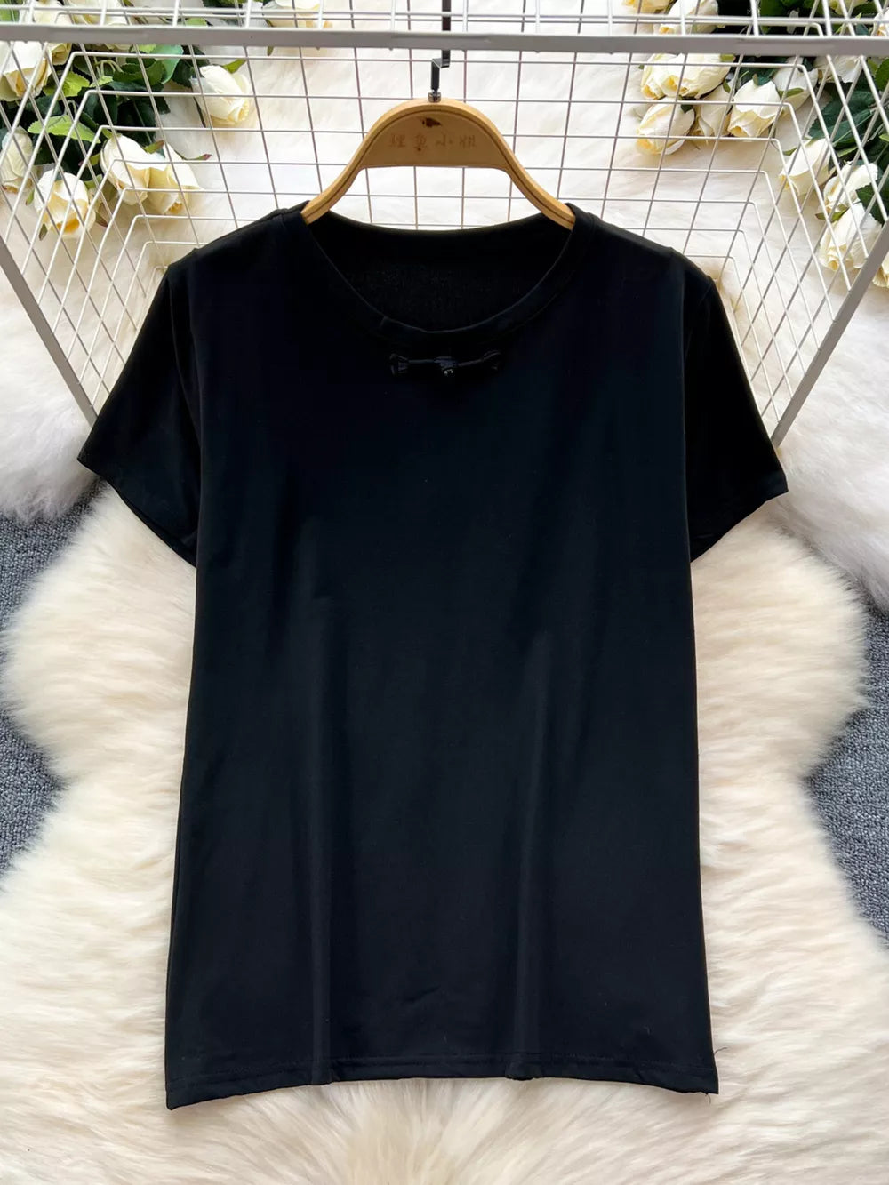 Black cotton t-shirt with short sleeves and a knotted detail at the neckline.