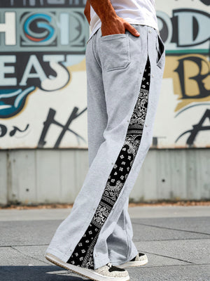 Light gray sweatpants with wide legs and a black bandana print side stripe with snaps.