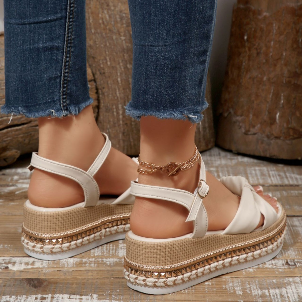 White bow knot wedge sandals with braided trim and ankle buckle, styled with a gold anklet.