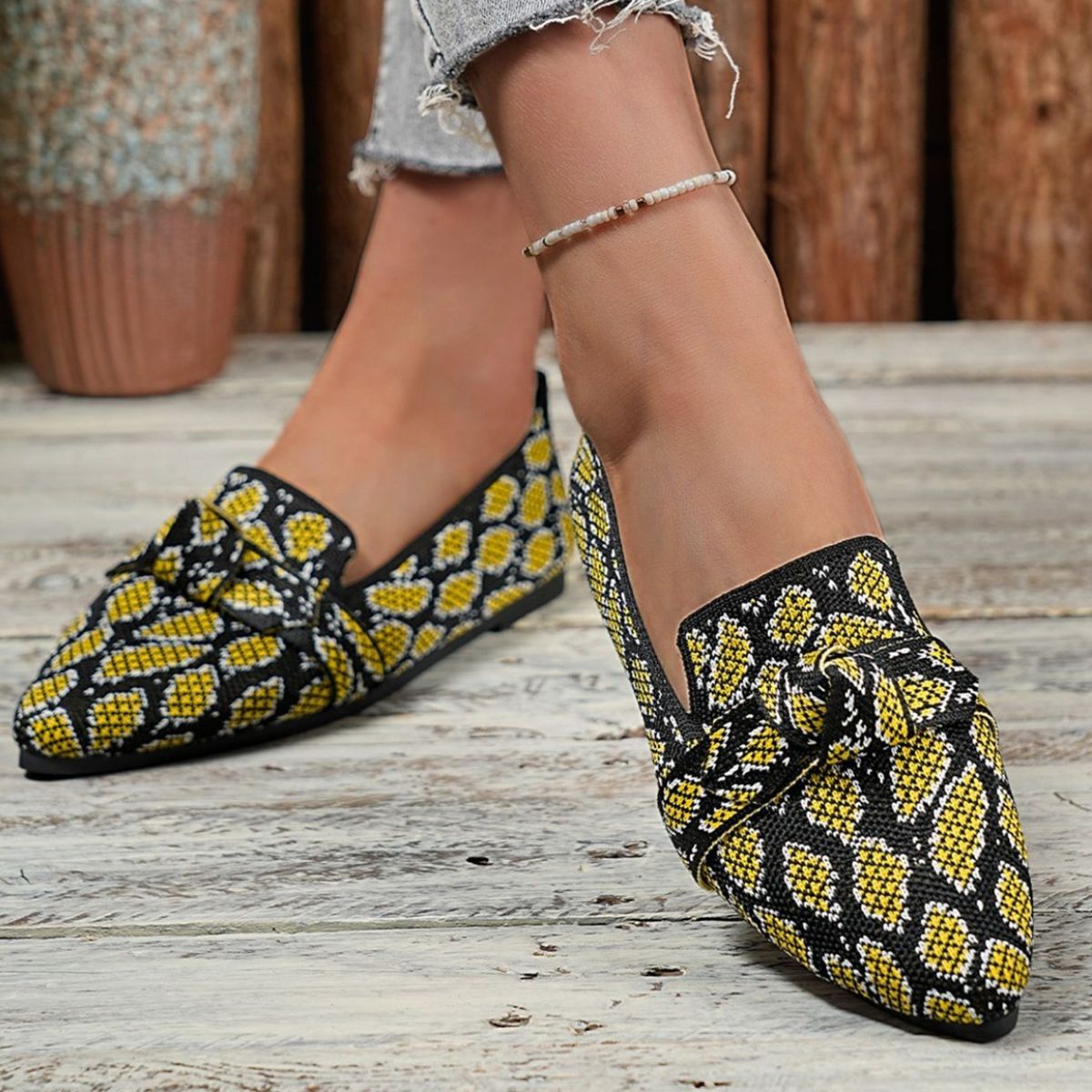 Yellow and black abstract print slip-on flats with knot detail.