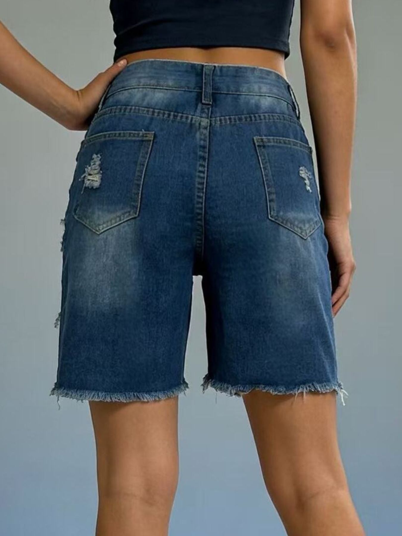 Distressed dark blue denim shorts with frayed hem and ripped details.
