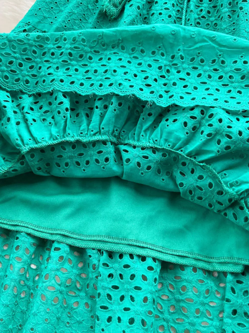 Green eyelet tiered maxi skirt with cutout details and a tassel drawstring.