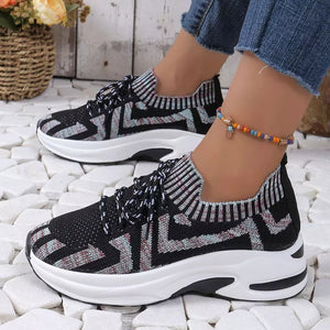 Geometric knit platform sneakers with black, white, and multi-color zigzag pattern and white soles.