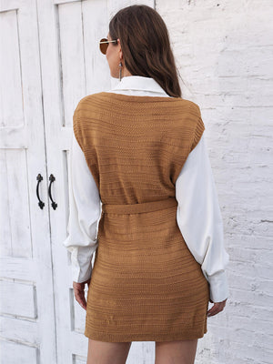Camel knit vest dress with tie and slit, styled over a white shirt.