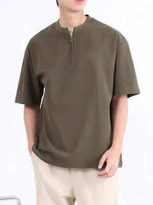 Men's dark green cotton half-zip t-shirt with short sleeves and a relaxed fit.