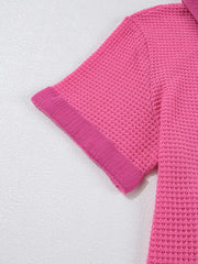Pink waffle-knit maternity shirt with short sleeves and a textured cuff detail.