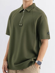 Army green cotton polo with metallic half-zip and button details.