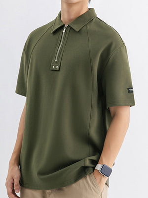 Army green cotton polo with metallic half-zip and button details.