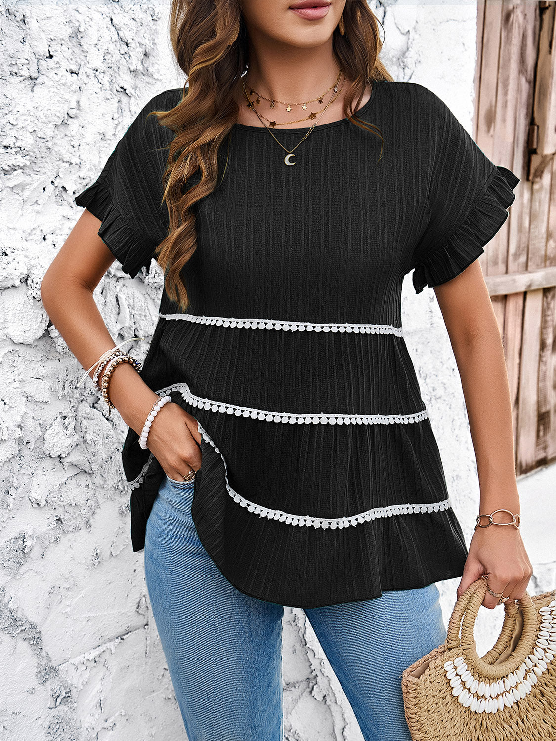 Black ribbed tiered ruffle trim blouse with short sleeves and a round neckline.