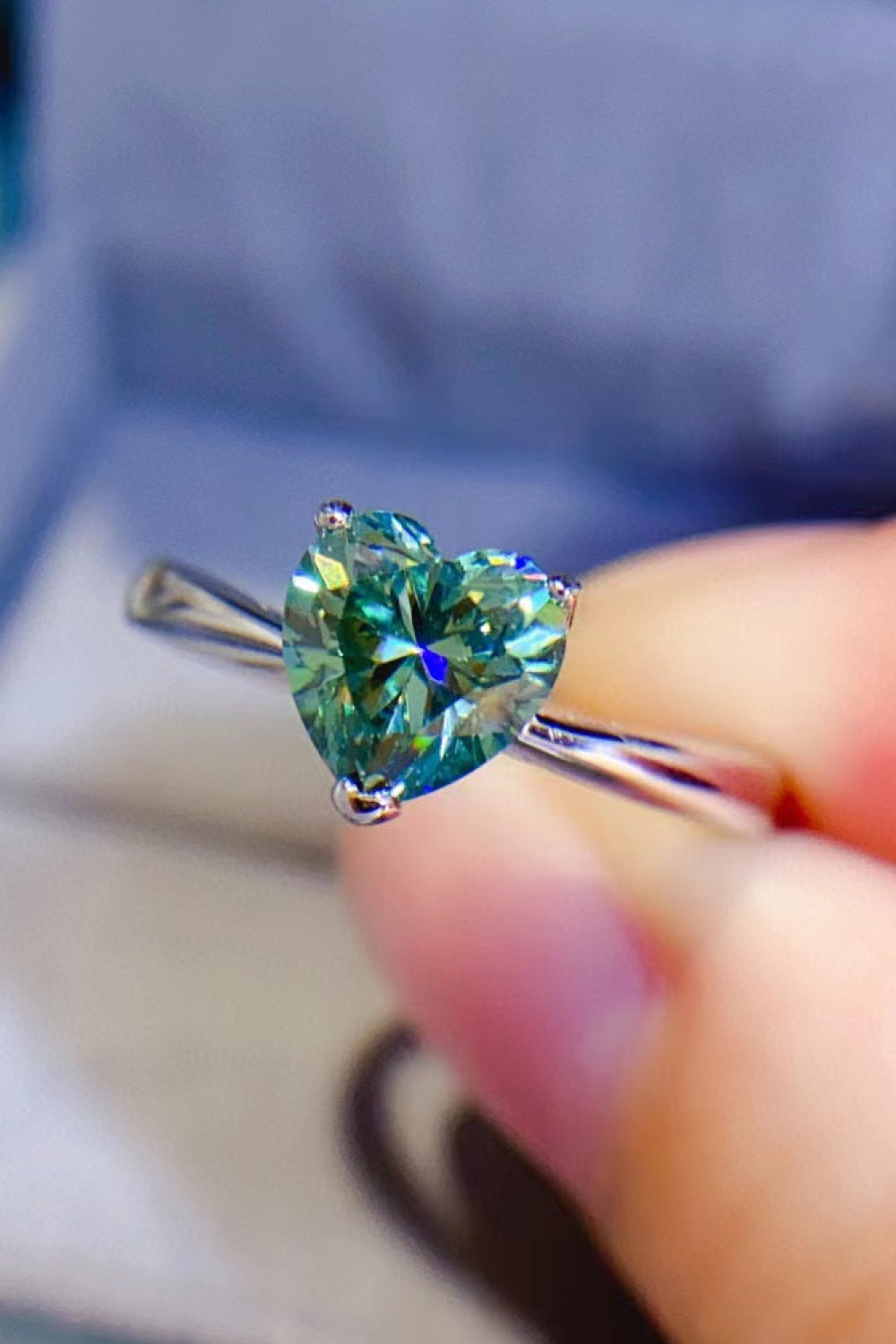 Green heart moissanite solitaire ring with a silver band.