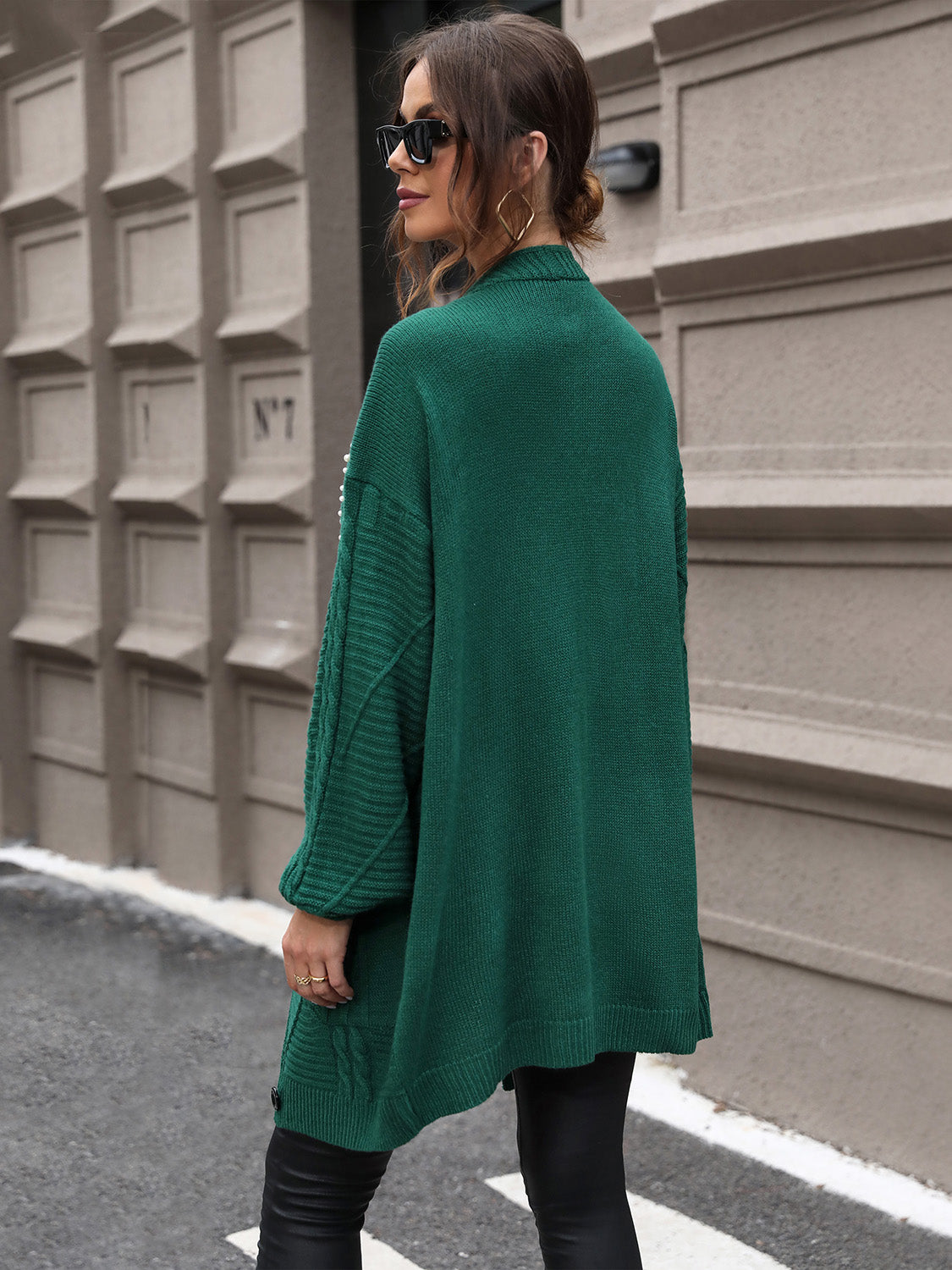 Green cable knit cardigan with pearl embellishments on the sleeves and a relaxed fit.