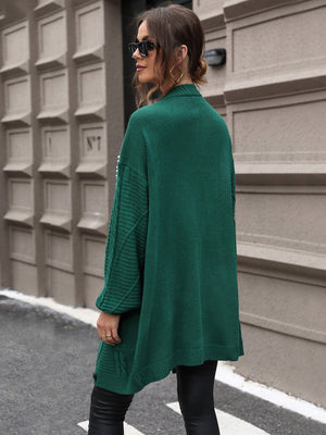 Green cable knit cardigan with pearl embellishments on the sleeves and a relaxed fit.