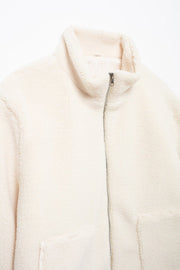 White sherpa jacket with stand collar and zipper closure.