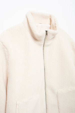 White sherpa jacket with stand collar and zipper closure.
