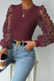 Wine knit top with sheer floral appliqué sleeves and crew neck.