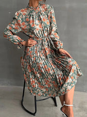 Green floral midi dress with pleated skirt, ruffled mock neck, and long sleeves.