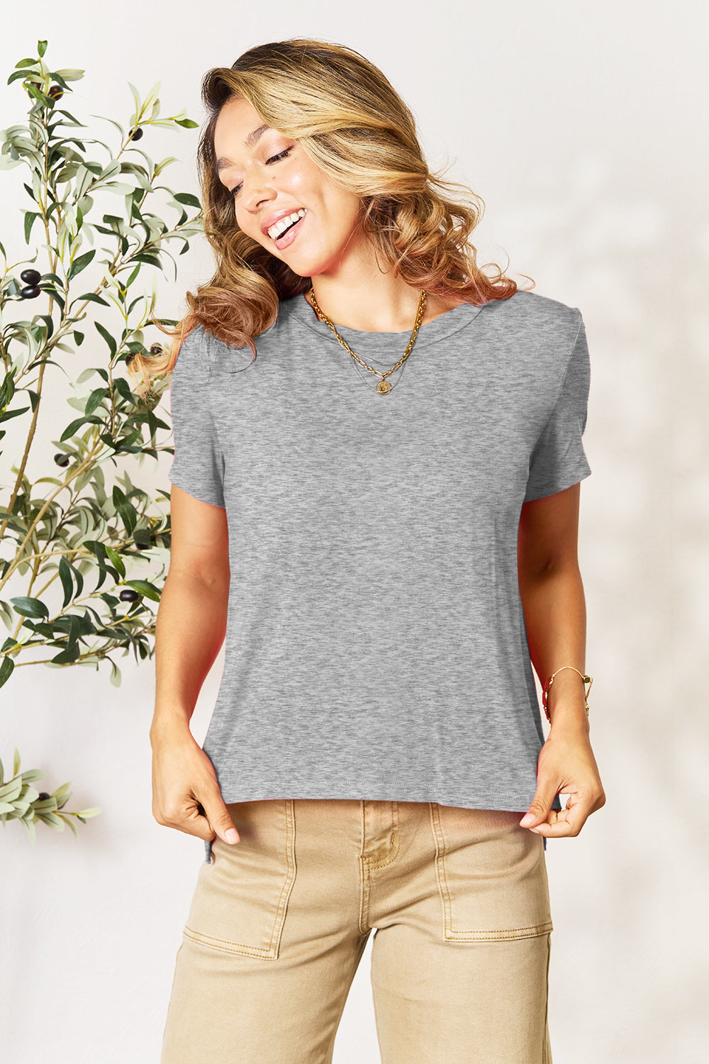 Slit hemline crew neck tee in gray bamboo blend with short sleeves, styled with a necklace.