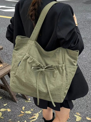Olive green nylon tote bag with drawstring and bow detail, featuring exterior pockets.
