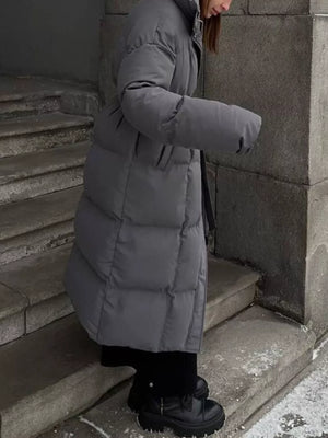Dark gray padded puffer trench coat with tie-belt, long sleeves, and a stand-up collar.