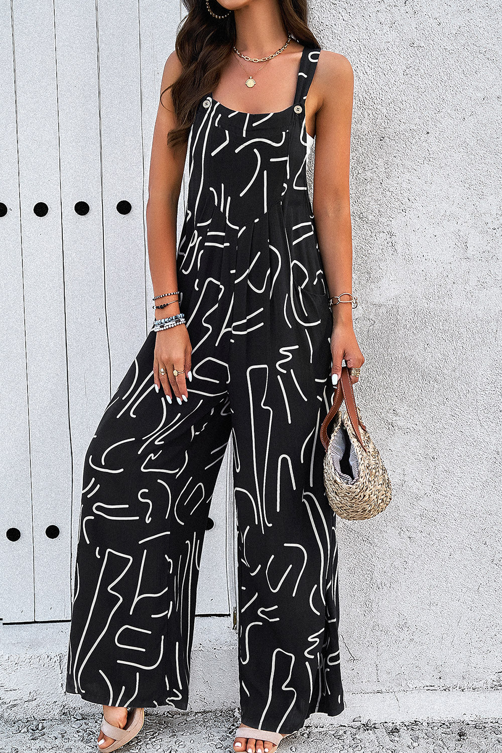 Black abstract scribble wide leg jumpsuit with button straps and side slits.
