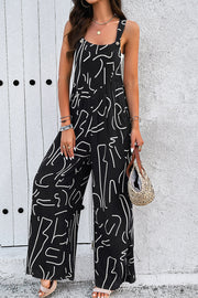Black abstract scribble wide leg jumpsuit with button straps and side slits.