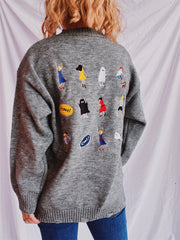 Dark gray relaxed knit sweater with embroidered characters and patches.