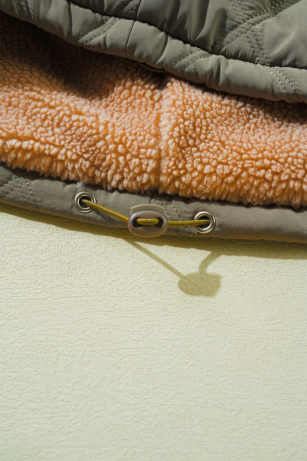 Sage quilted utility jacket with cozy sherpa lining and drawstring detail.