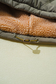Sage quilted utility jacket with cozy sherpa lining and drawstring detail.