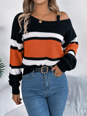 Asymmetric stripe knit sweater with gold shoulder detail, orange, white, and black stripes.