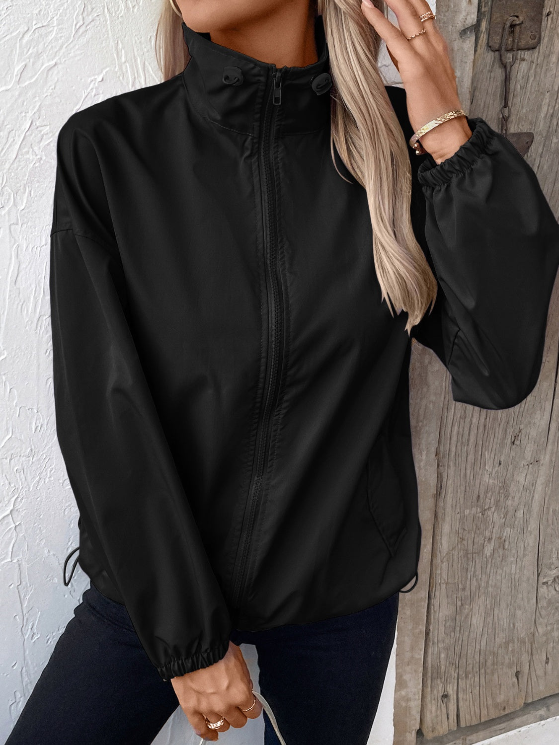 Black nylon bomber jacket with drawstring hem and elastic cuffs.
